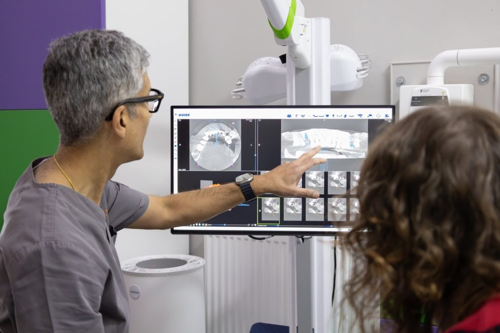Dr Neeraj Puri talking a patient through her 3D implant scan on the X-Guide planning screen, Integrated Dentalcare, Edinburgh